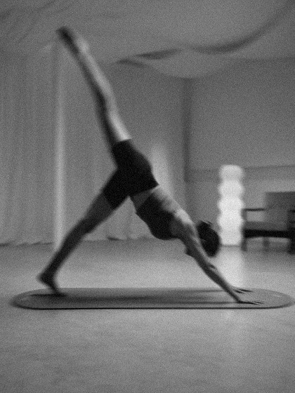 A woman doing a three-legged downward dog on a mat